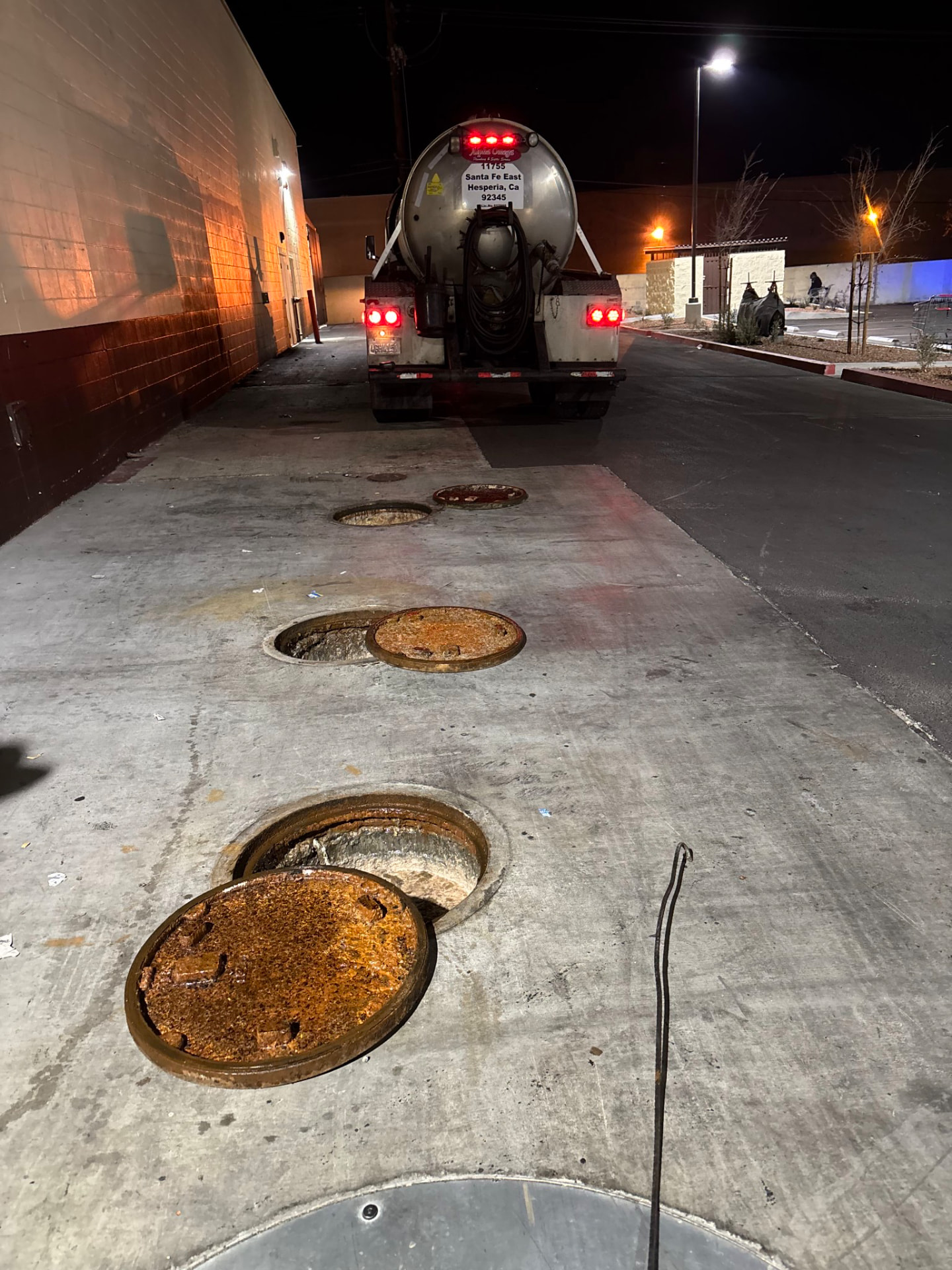 Multiple grease interceptor access lids opened for pumping behind a shopping center in La Quinta, California