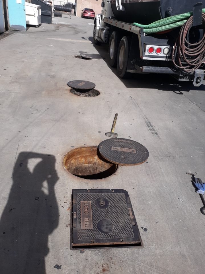 Daytime grease interceptor service with lids removed and vacuum truck staged in Temecula, California